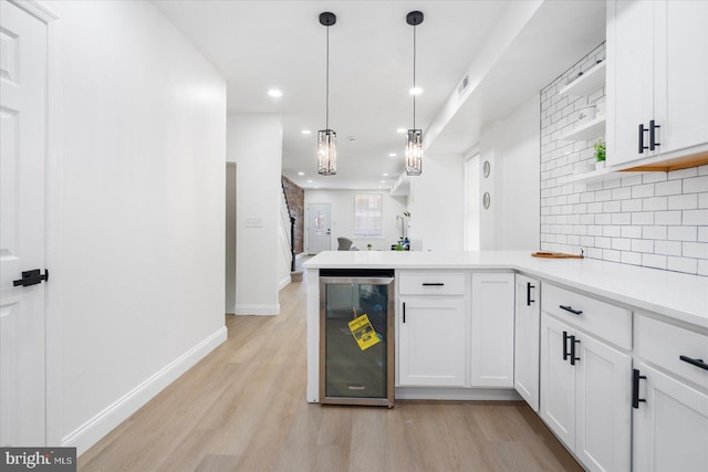 kitchen with pendant lighting, light hardwood / wood-style flooring, beverage cooler, decorative backsplash, and white cabinetry