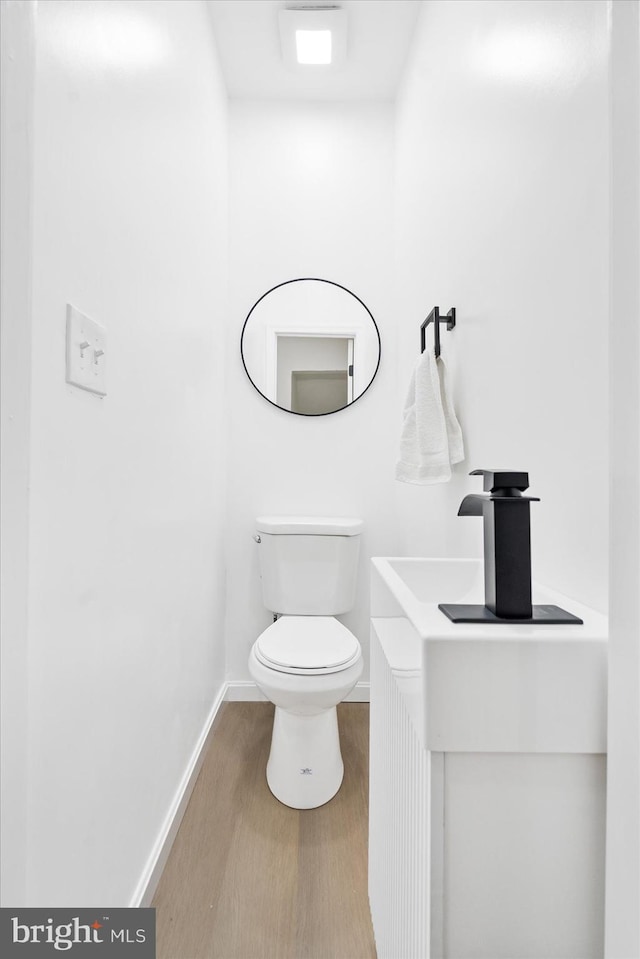 bathroom with toilet, sink, and hardwood / wood-style flooring