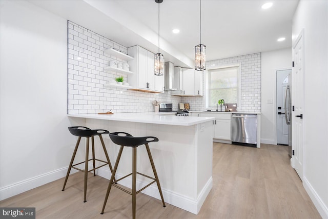 kitchen featuring light hardwood / wood-style flooring, appliances with stainless steel finishes, a breakfast bar, kitchen peninsula, and white cabinets