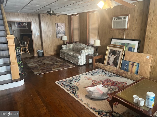 sitting room with wood walls, ceiling fan, dark hardwood / wood-style floors, and a wall unit AC