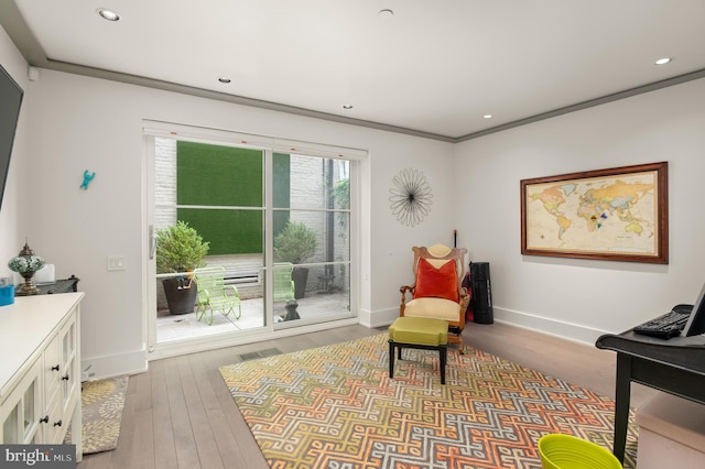 living area with crown molding and hardwood / wood-style flooring