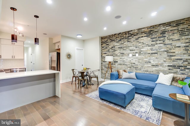 living room with brick wall and light hardwood / wood-style floors