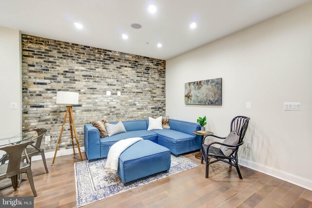 living room with brick wall and hardwood / wood-style flooring