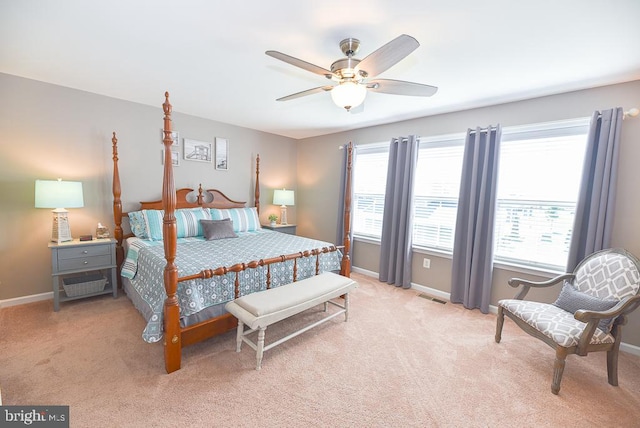 bedroom featuring ceiling fan, light carpet, and multiple windows