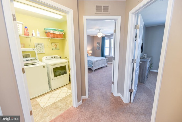 washroom featuring washing machine and dryer, ceiling fan, and light colored carpet