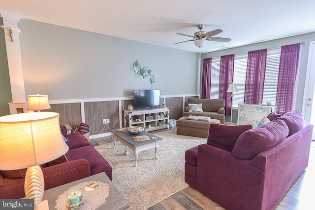 living room featuring ceiling fan, wooden walls, and wood-type flooring