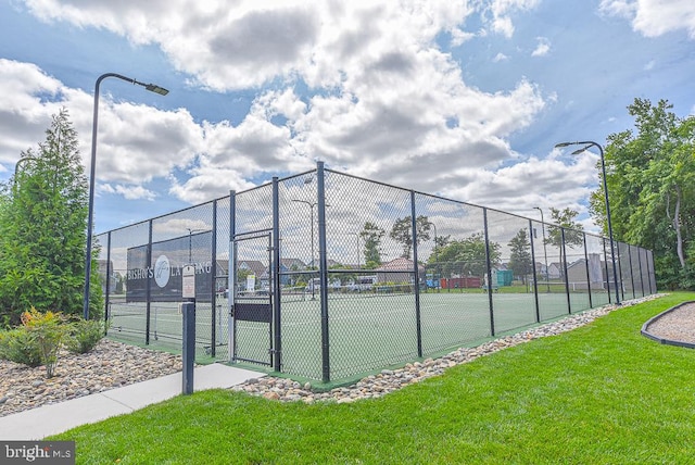 view of tennis court featuring a lawn