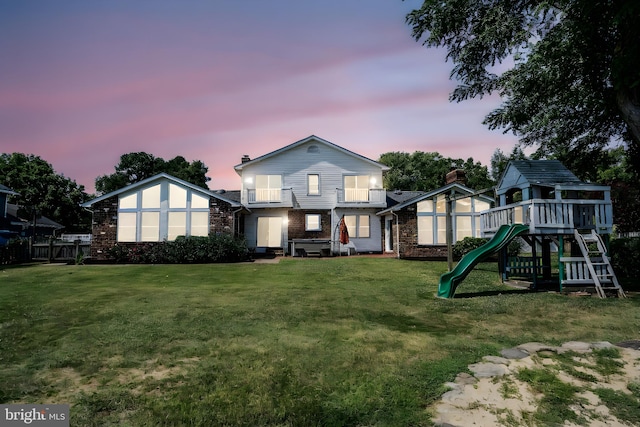 exterior space with a playground, a yard, brick siding, and a chimney