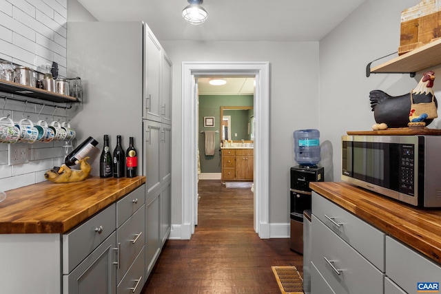 kitchen with gray cabinets, dark wood-type flooring, tasteful backsplash, and butcher block countertops