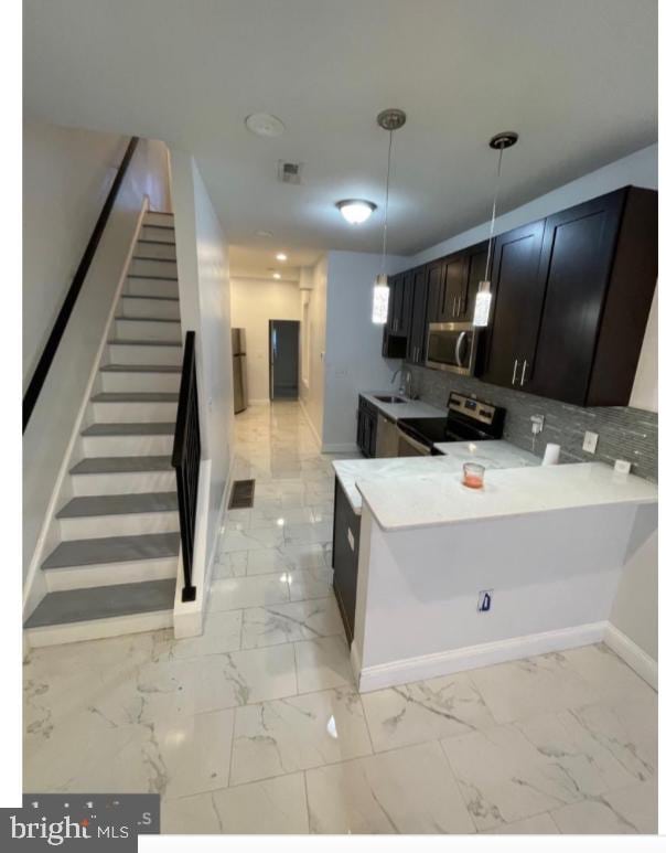 kitchen with hanging light fixtures, stainless steel appliances, sink, kitchen peninsula, and tasteful backsplash