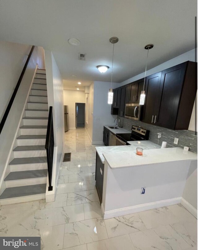 kitchen featuring appliances with stainless steel finishes, tasteful backsplash, hanging light fixtures, kitchen peninsula, and sink