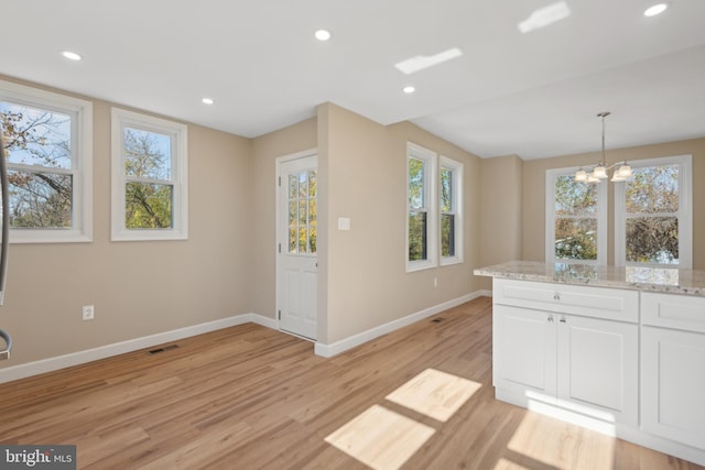 kitchen with white cabinetry, plenty of natural light, pendant lighting, and light hardwood / wood-style flooring