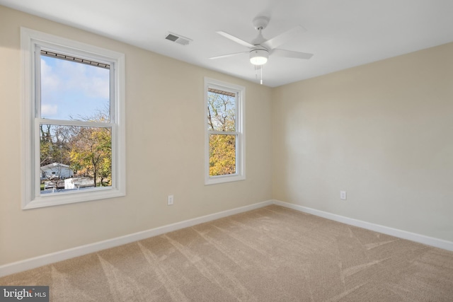 carpeted spare room featuring plenty of natural light and ceiling fan