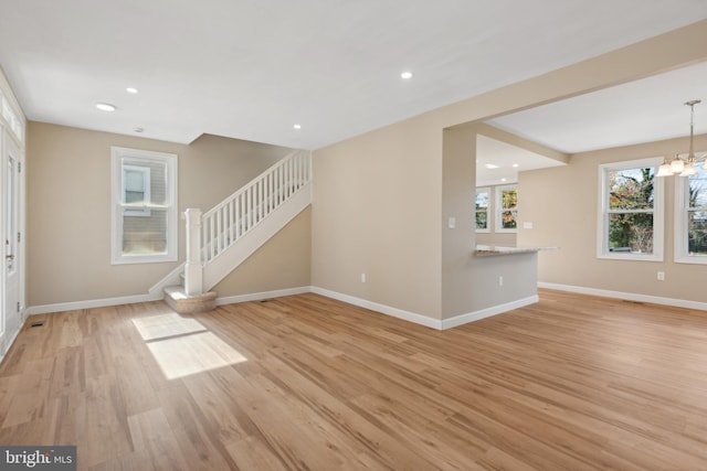 unfurnished living room featuring light hardwood / wood-style floors and a notable chandelier