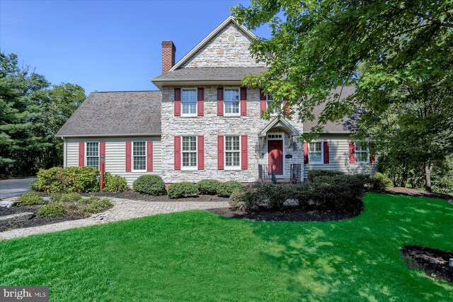 colonial-style house featuring a front yard