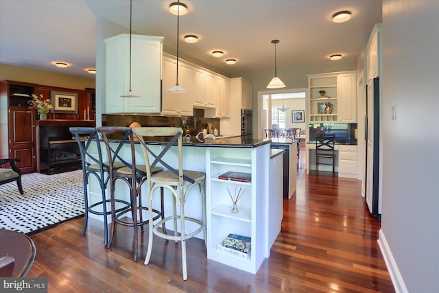 kitchen featuring decorative light fixtures, dark hardwood / wood-style flooring, kitchen peninsula, black oven, and white cabinets