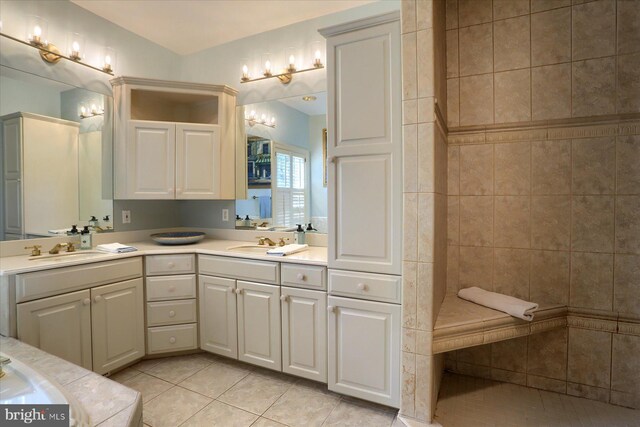 bathroom with tile patterned flooring, vanity, and tiled tub