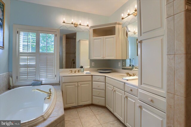 bathroom with vanity, a relaxing tiled tub, and tile patterned floors