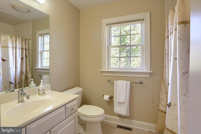 bathroom with a wealth of natural light, vanity, toilet, and tile patterned flooring