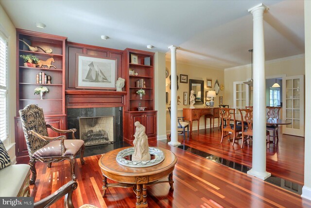 living room with crown molding, a high end fireplace, ornate columns, dark hardwood / wood-style floors, and built in features