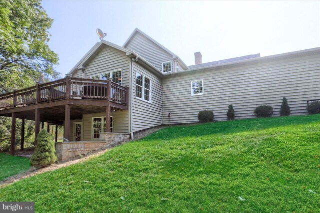 back of house featuring a lawn and a deck