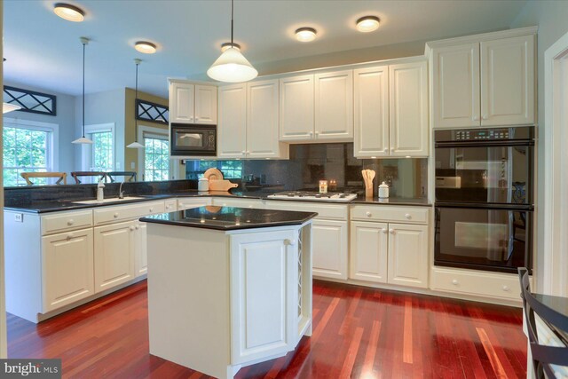 kitchen featuring black appliances, a center island, hanging light fixtures, sink, and white cabinetry