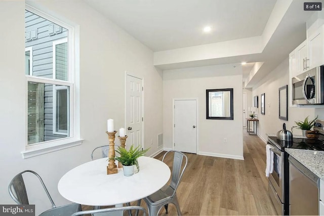 kitchen featuring stainless steel appliances, light hardwood / wood-style floors, and white cabinetry