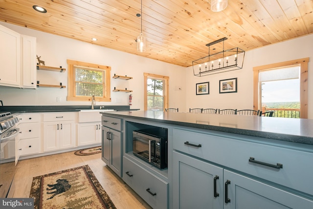 kitchen with white cabinets, plenty of natural light, and hanging light fixtures