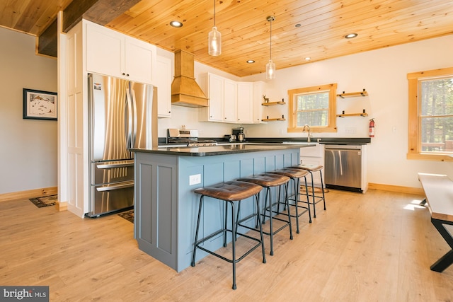 kitchen with white cabinets, stainless steel appliances, wooden ceiling, a center island, and custom exhaust hood