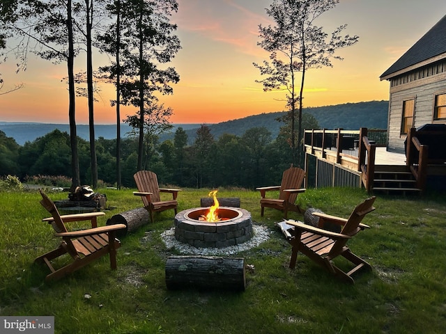 yard at dusk with an outdoor fire pit and a deck with water view