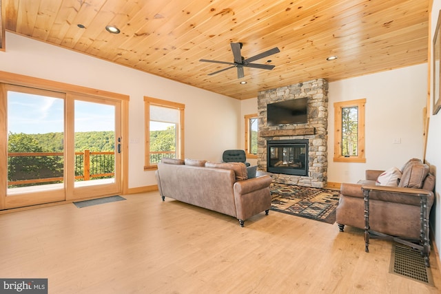 living room with wooden ceiling, a healthy amount of sunlight, a stone fireplace, and ceiling fan