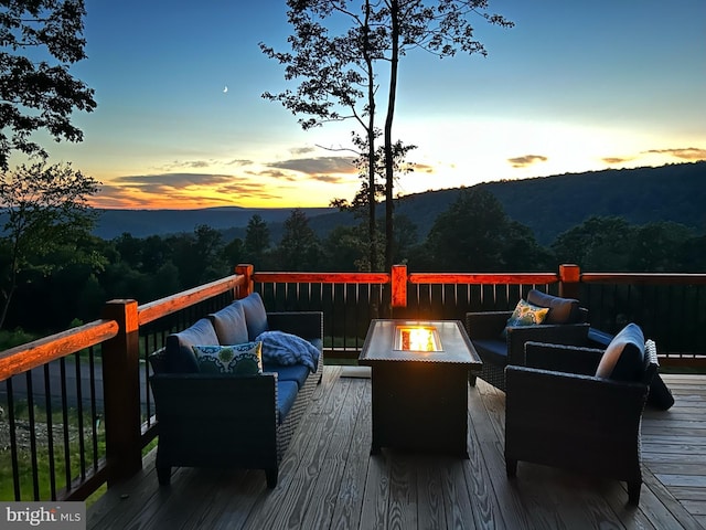 deck at dusk featuring a mountain view and an outdoor living space with a fire pit