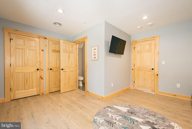 unfurnished bedroom with wood-type flooring and ensuite bath