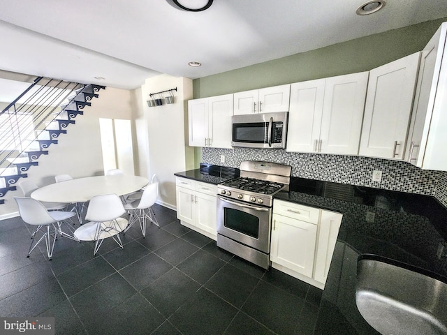 kitchen with appliances with stainless steel finishes, white cabinetry, backsplash, and sink