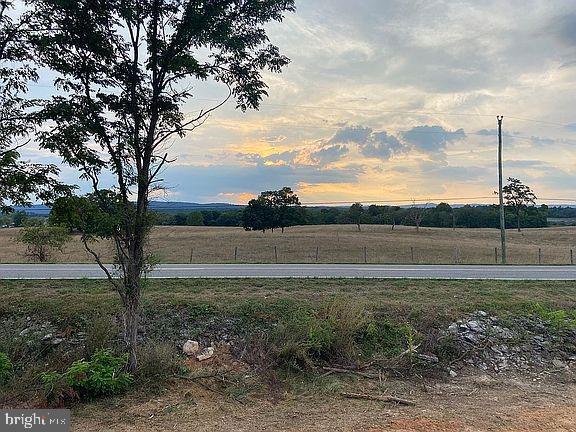 yard at dusk featuring a rural view