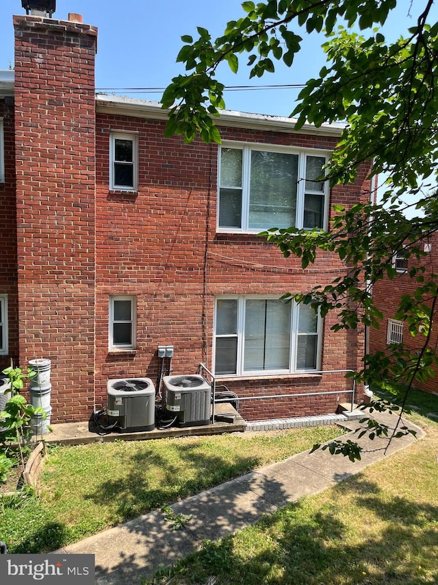 rear view of property with a lawn and central air condition unit