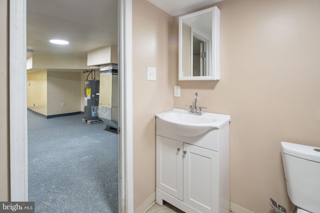 bathroom featuring electric water heater, vanity, and toilet