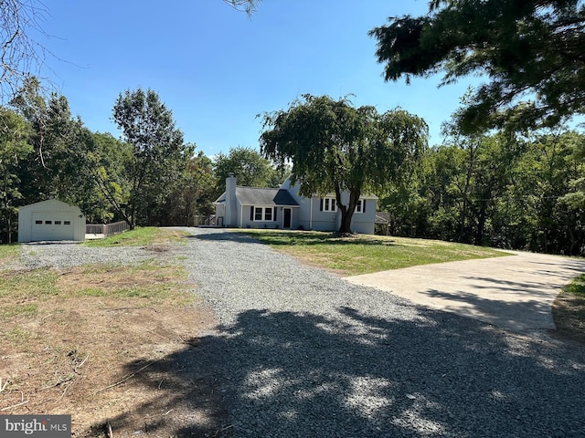 view of front of home featuring a garage, a front lawn, and an outbuilding