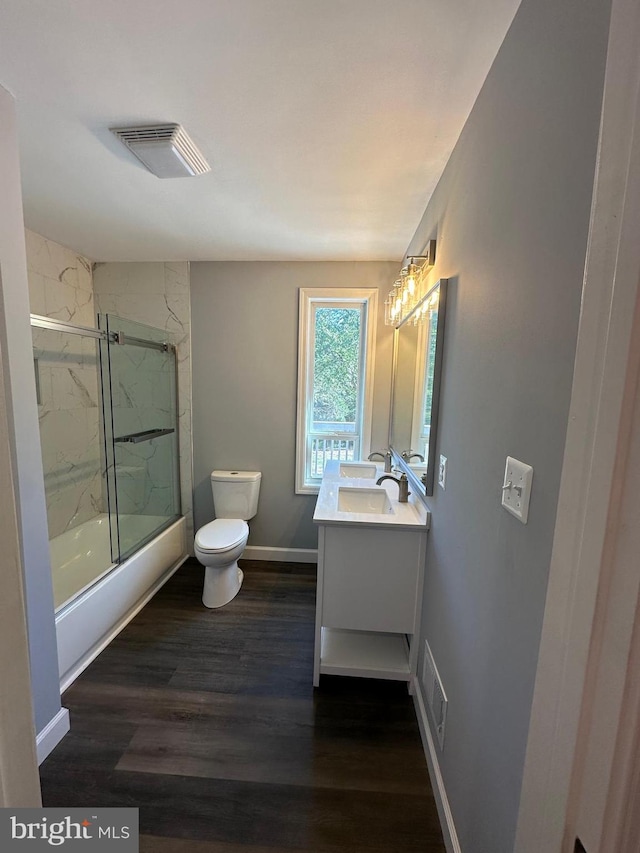 full bathroom featuring wood-type flooring, enclosed tub / shower combo, vanity, and toilet