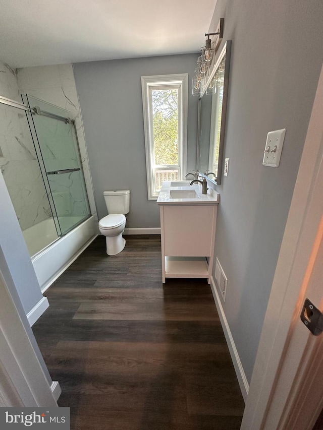 full bathroom featuring shower / bath combination with glass door, toilet, vanity, and wood-type flooring