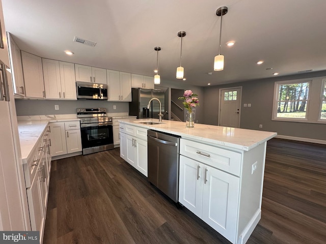 kitchen with dark hardwood / wood-style floors, a center island with sink, hanging light fixtures, white cabinets, and appliances with stainless steel finishes