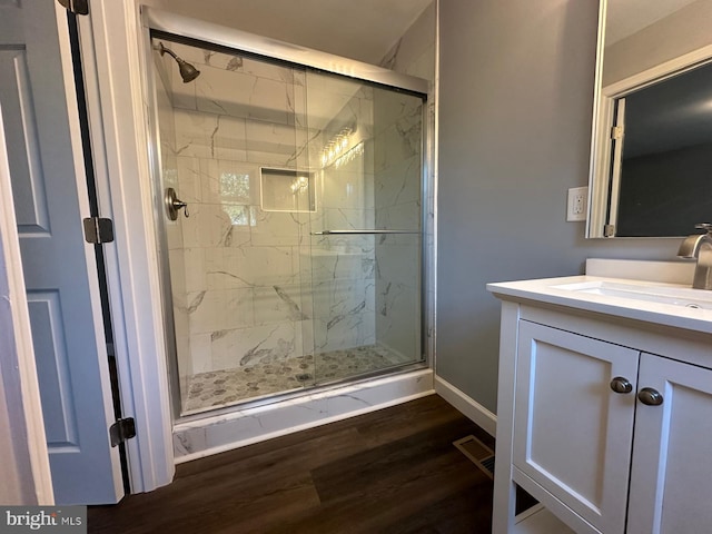 bathroom featuring hardwood / wood-style floors, a shower with door, and vanity