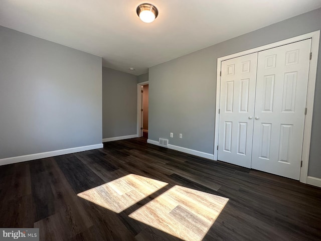 unfurnished bedroom featuring a closet and dark hardwood / wood-style floors