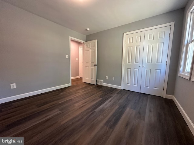 unfurnished bedroom featuring dark wood-type flooring and a closet