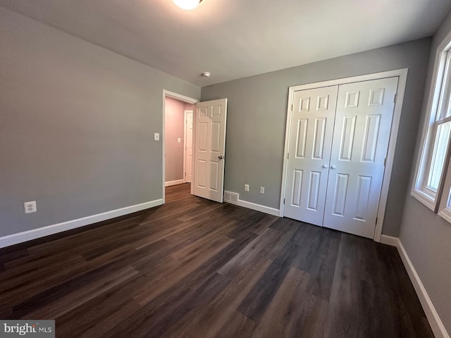 unfurnished bedroom featuring dark wood-type flooring and a closet