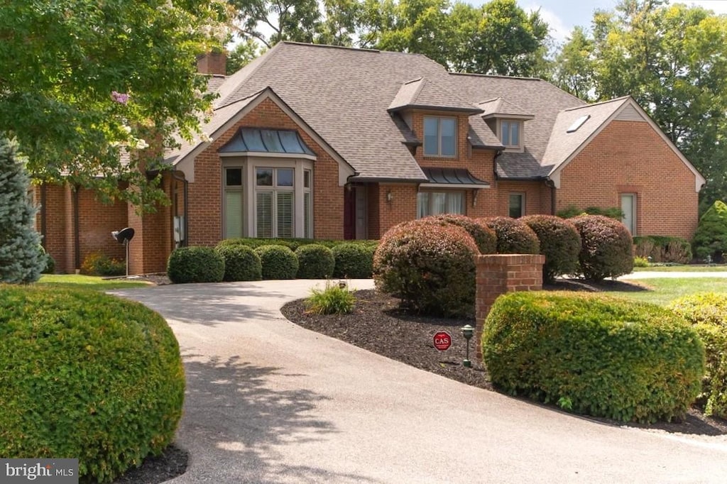 view of front facade featuring brick siding, driveway, and a shingled roof