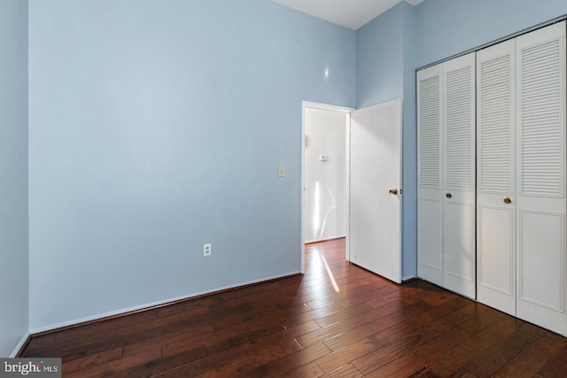 unfurnished bedroom with dark hardwood / wood-style flooring and a closet