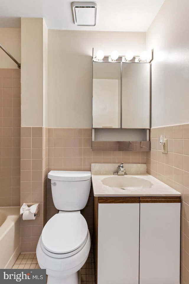 full bathroom with toilet, vanity, tile walls, and tile patterned floors