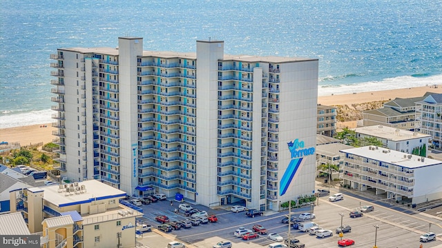 view of building exterior featuring a water view and a beach view