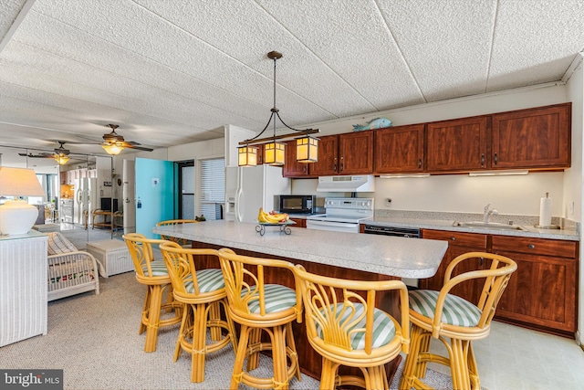 kitchen with hanging light fixtures, sink, black appliances, ceiling fan, and a kitchen bar